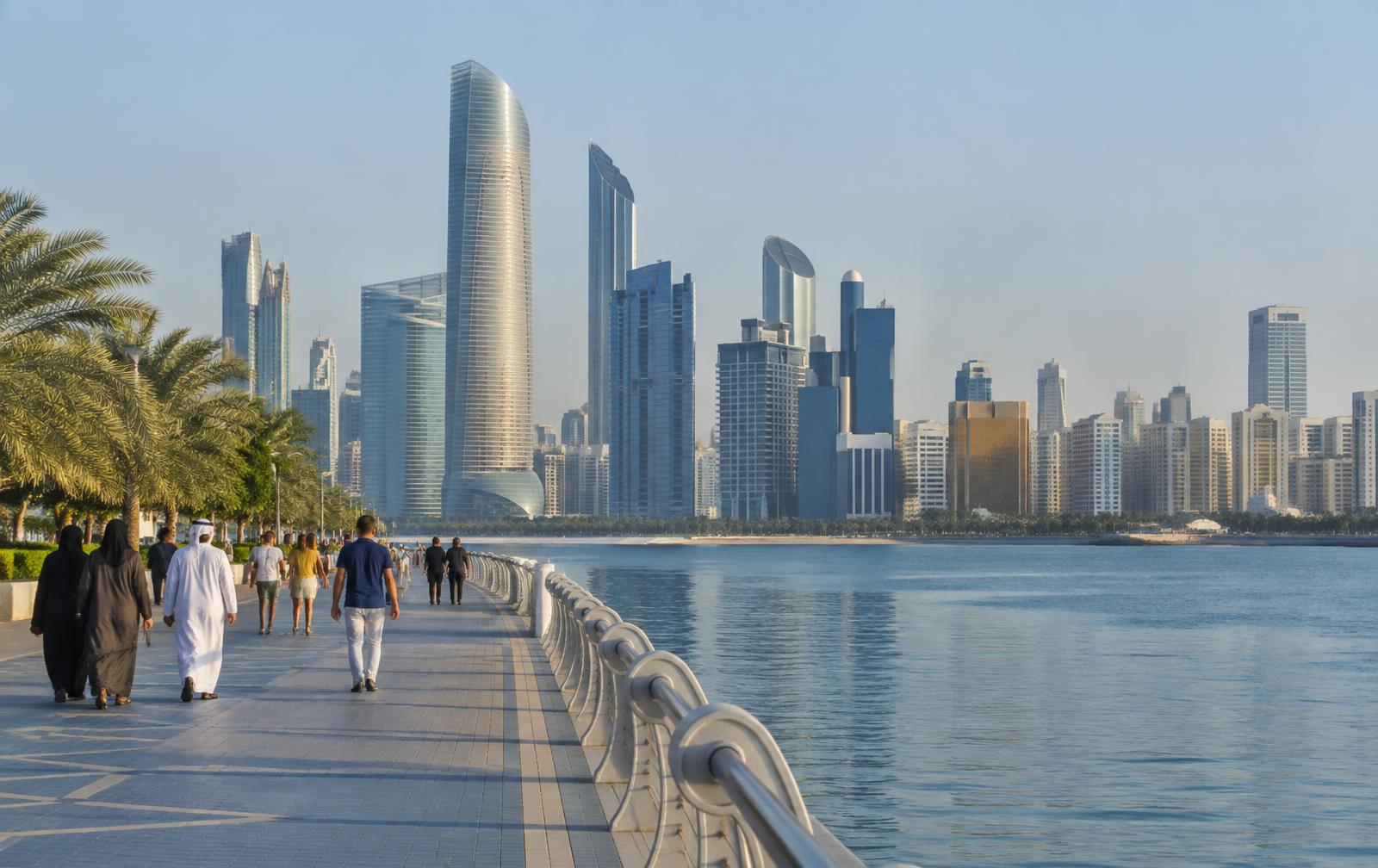 Wandelaars langs de Corniche met de skyline van Abu Dhabi aan het water